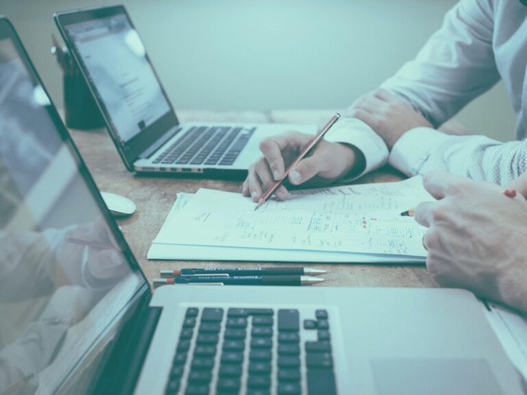 Image of 2 people working together with paper and laptops